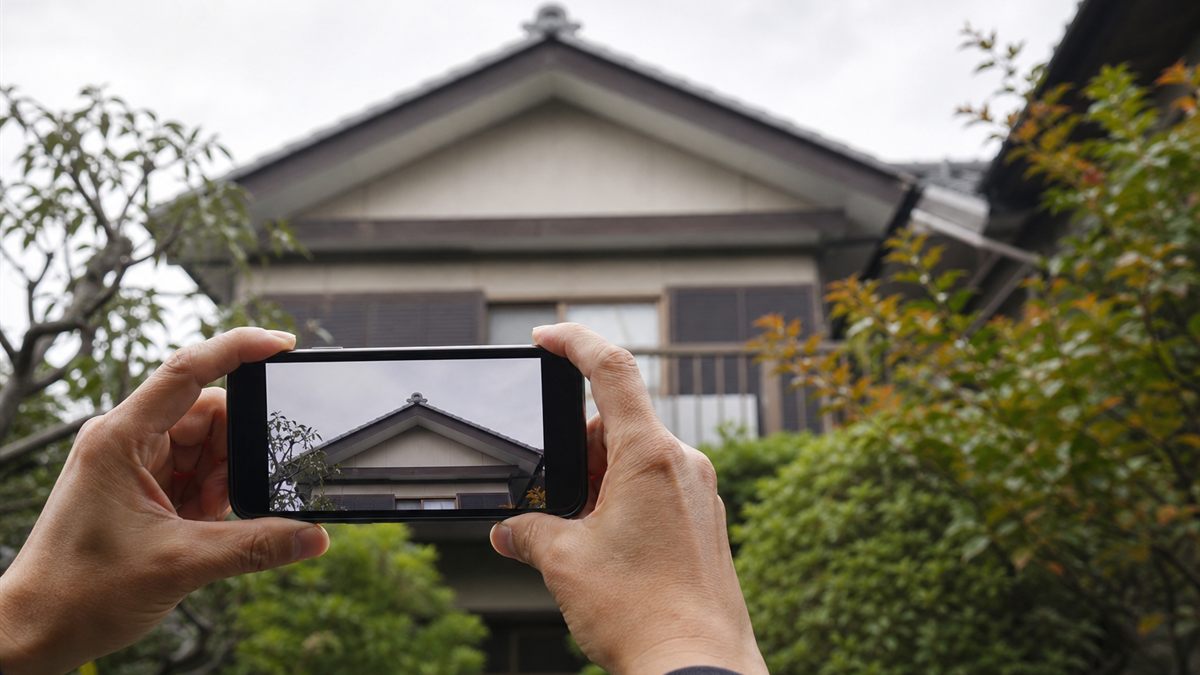 地上から屋根の棟をスマートフォンで撮る手元