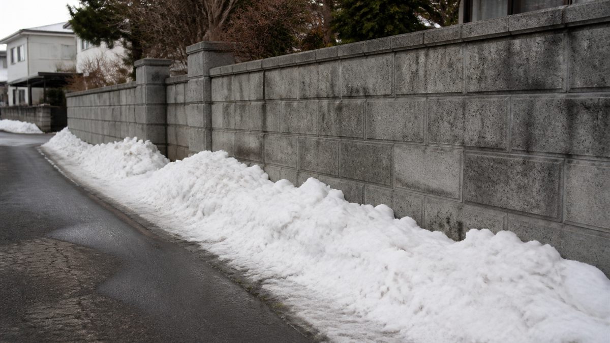 雪が寄せられたブロック塀