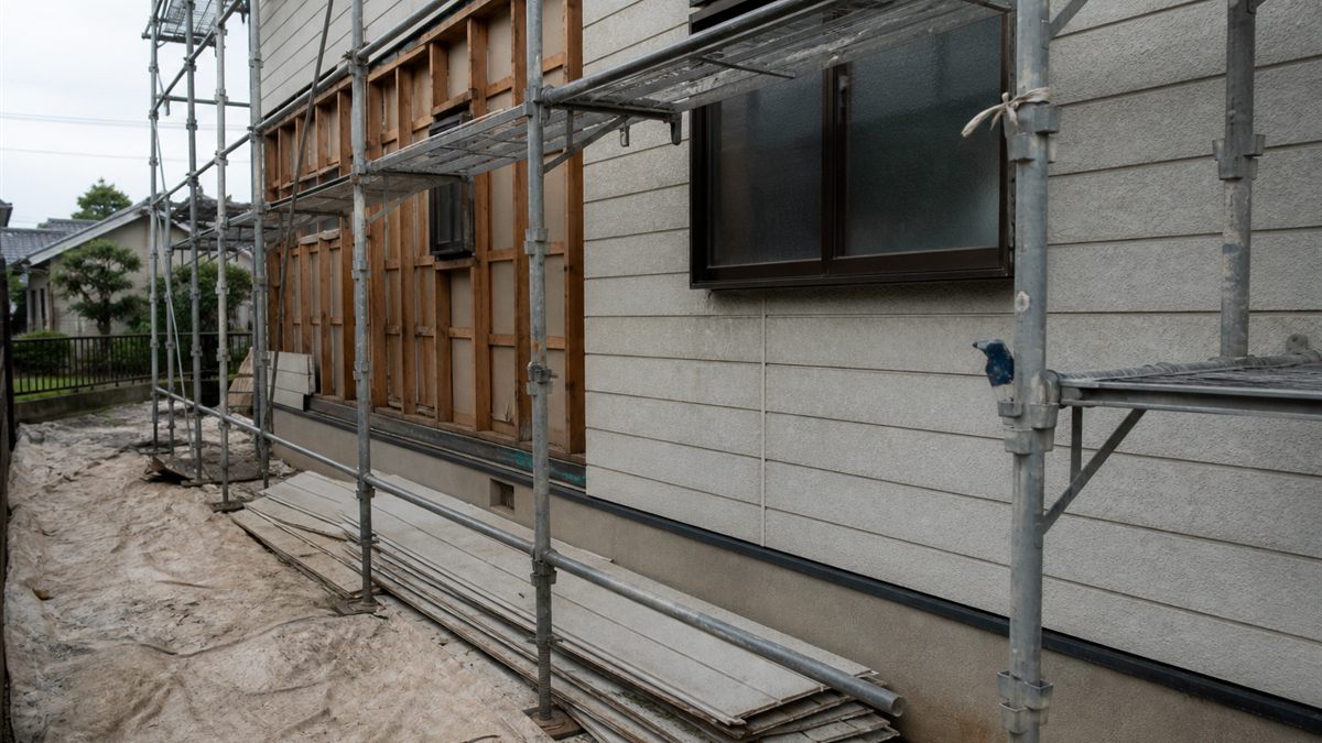 足場が架かり外壁材の一部が外された住宅の壁面