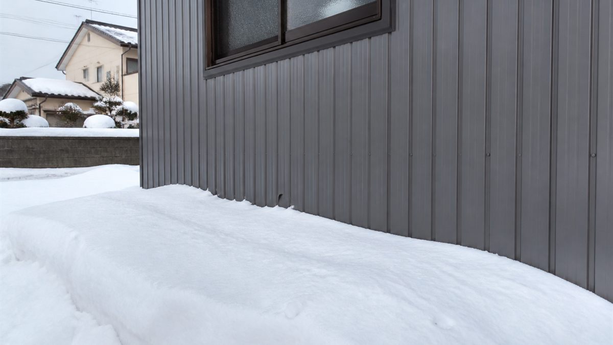 壁際に雪が積もった住宅