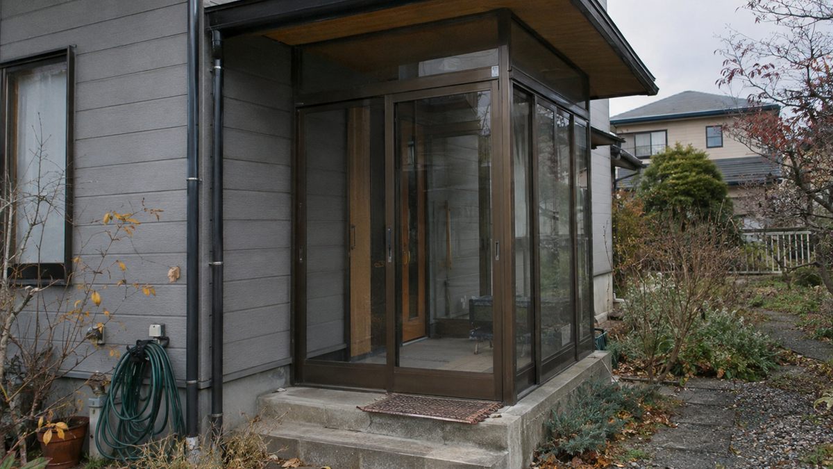 玄関ポーチを囲った風除室と既存の庇の関係が分かる住宅の外観