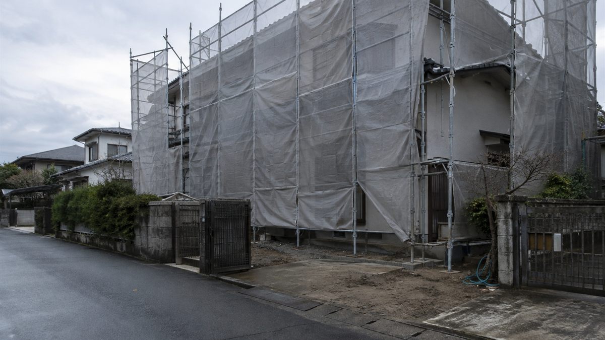 屋根に足場とシートが掛かった住宅