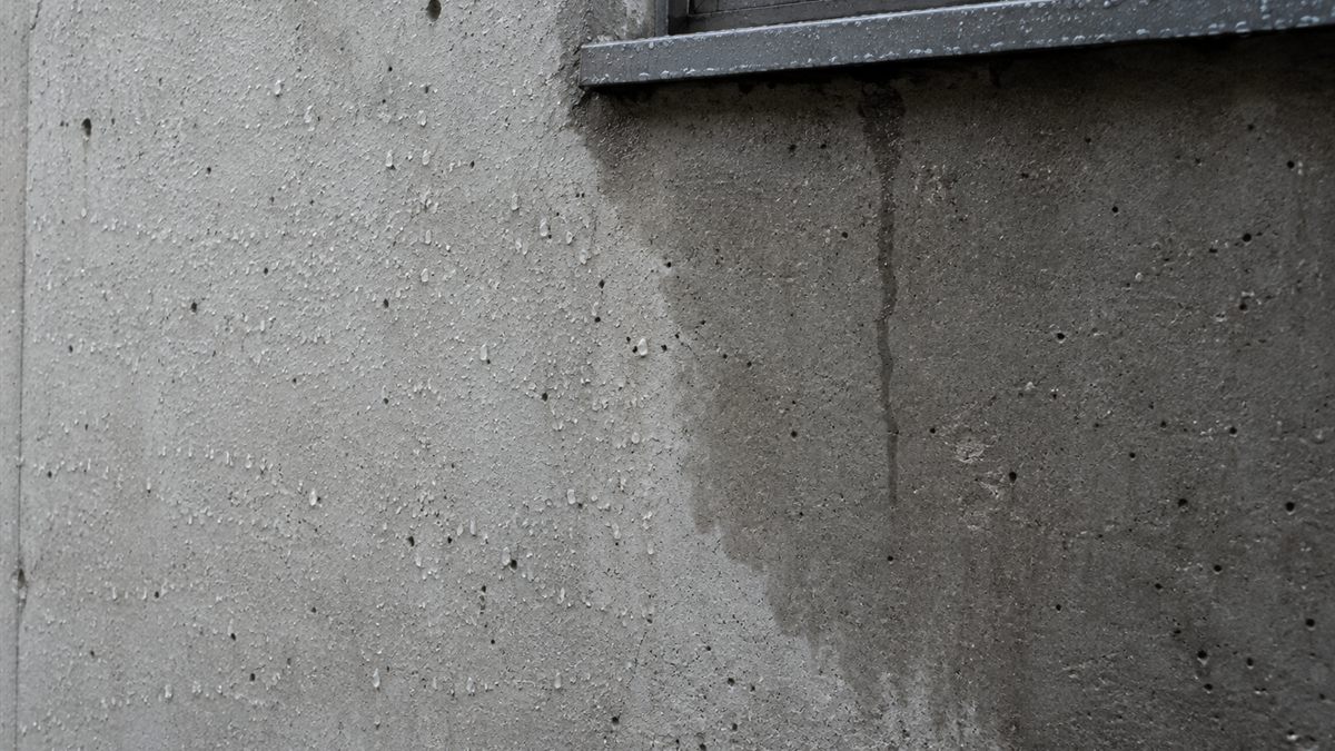 雨に濡れて色が濃く変わった打ちっぱなしの壁面